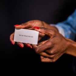Close-up of a woman's hands holding a motivational card with 'we do what we say'.