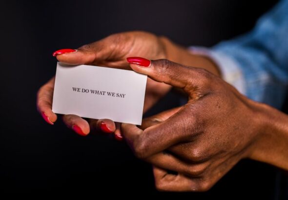 Close-up of a woman's hands holding a motivational card with 'we do what we say'.