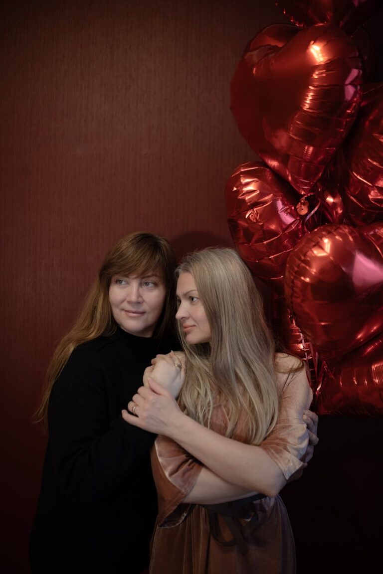 Warm embrace of mother and daughter beside red heart balloons, conveying love and affection.