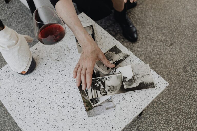 A contemplative moment with vintage photographs and a glass of red wine on a marble table.