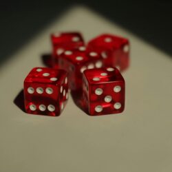 Five red dice with white dots photographed on a neutral background.