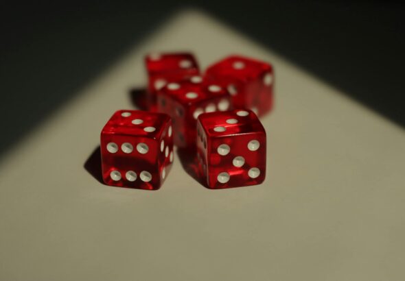Five red dice with white dots photographed on a neutral background.