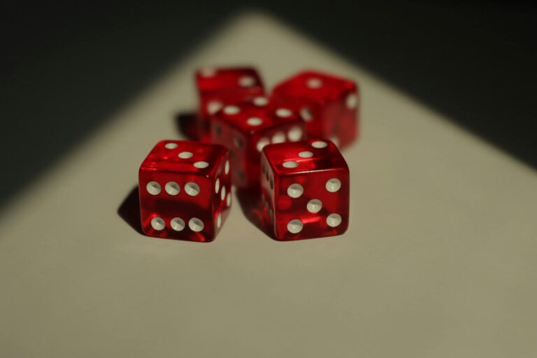 Five red dice with white dots photographed on a neutral background.