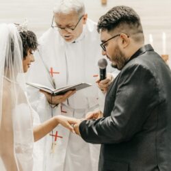 Bride and groom exchanging vows in a church ceremony led by a priest.