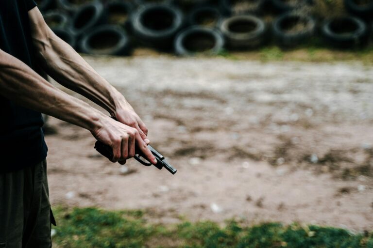 Close-up of a man handling a firearm during shooting practice outdoors.