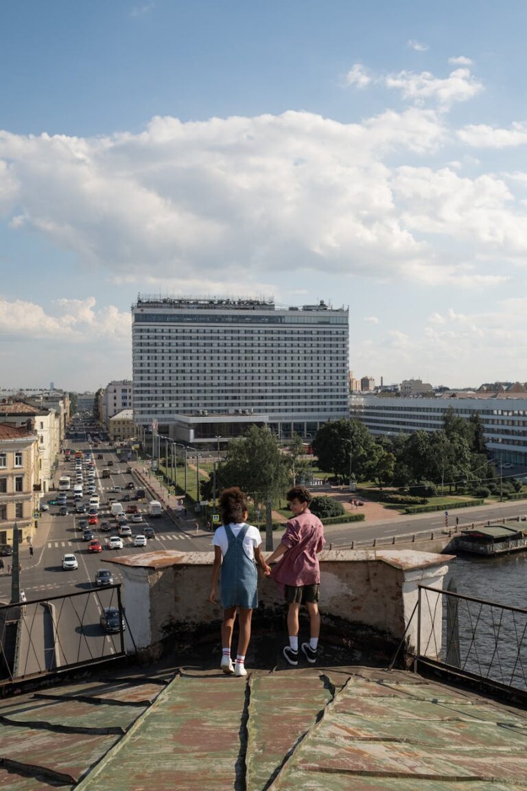 Teenagers holding hands on a rooftop overlooking cityscape, symbolizing young love and adventure.