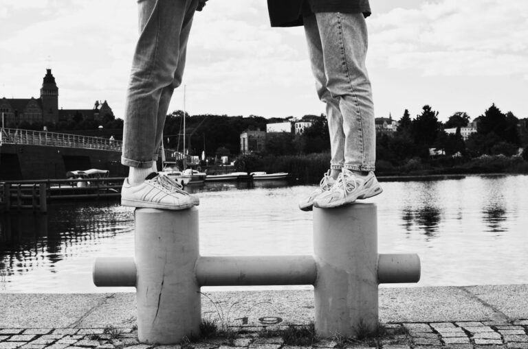 A romantic black and white photo of a couple standing on bollards by a river in Szczecinek, Poland.