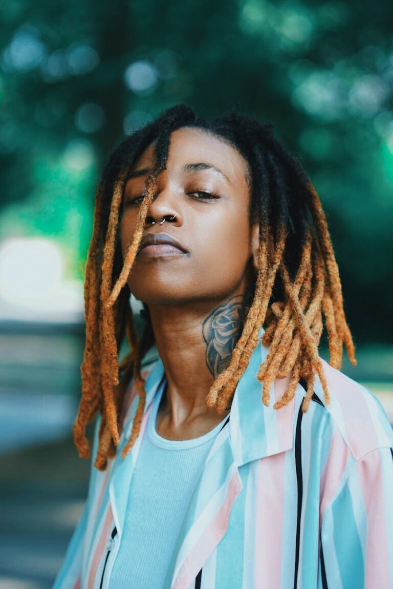 Outdoor portrait of a woman with dreadlocks and tattoos, wearing a colorful shirt in Atlanta.
