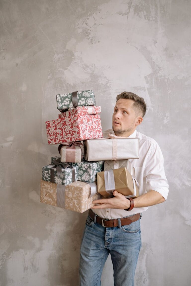 A man attempts to balance a large stack of wrapped gift boxes with a concerned expression.