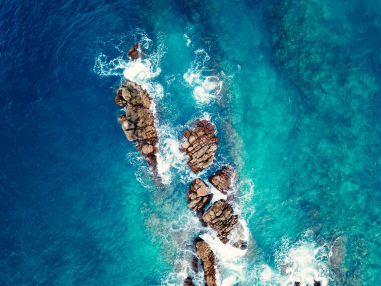 A stunning aerial shot showcasing the vibrant blue waters and rocky coastline of Aceh, Indonesia.