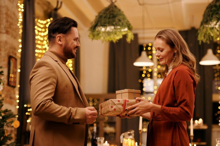 Joyful couple exchanging gifts in a festive indoor setting, capturing the warm spirit of the holiday season.
