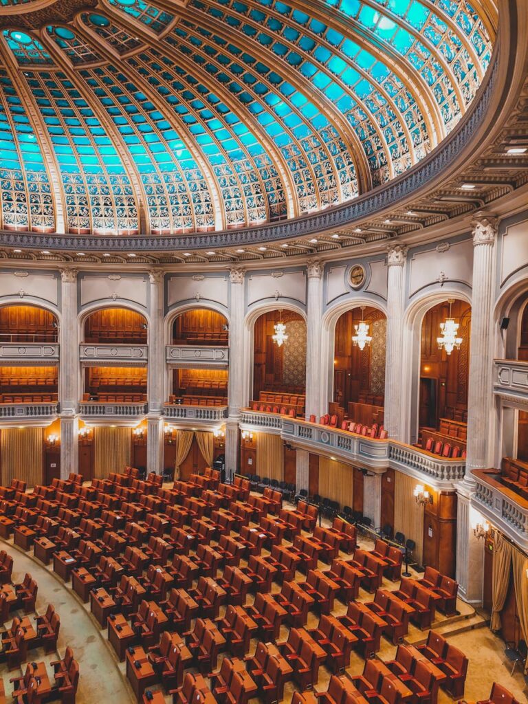 Majestic view of an ornate parliamentary chamber with a striking turquoise dome and plush seating.