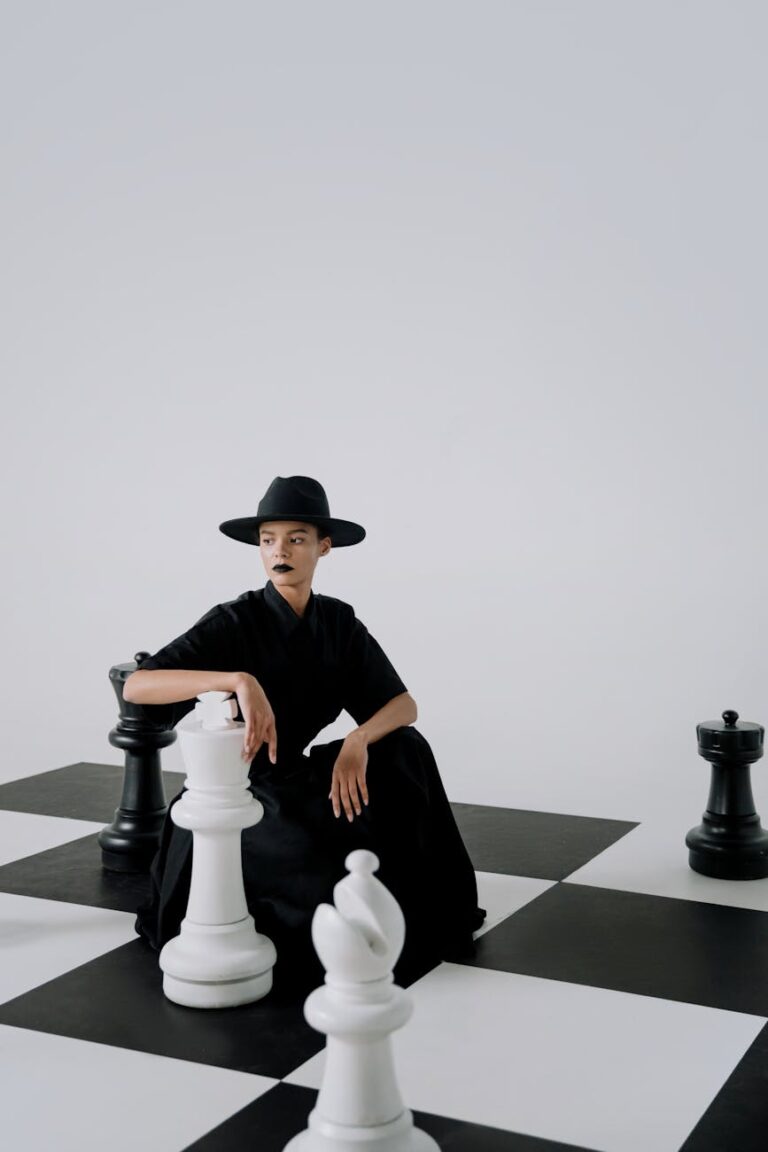 Conceptual fashion portrait featuring a model in black attire on a chessboard.