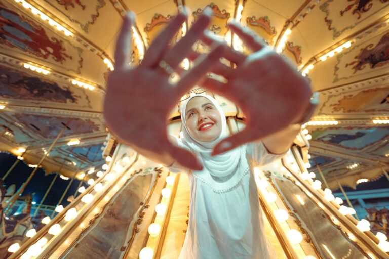 A joyful woman poses on a brightly lit carousel in Baghdad, adding charm to the lively scene.