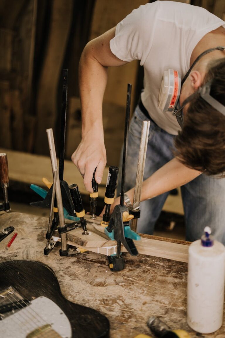 Adult man working with tools in a woodworking workshop, focused and using clamps.