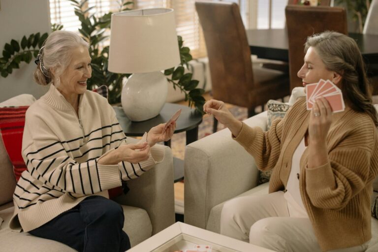 Two senior women playing cards and enjoying leisure time in a cozy living room.
