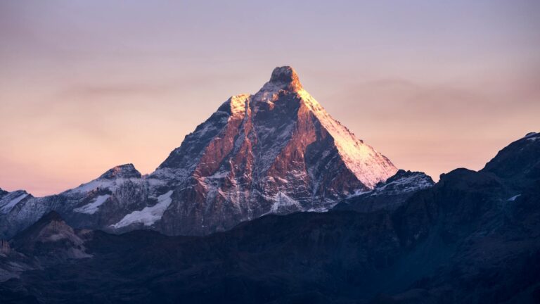 Stunning view of the Matterhorn mountain illuminated by the first light of sunrise against a colorful sky.