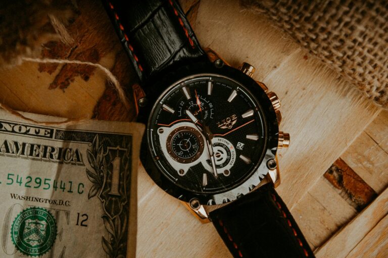 Close-up of a luxury wristwatch with a dollar bill on a wooden surface.