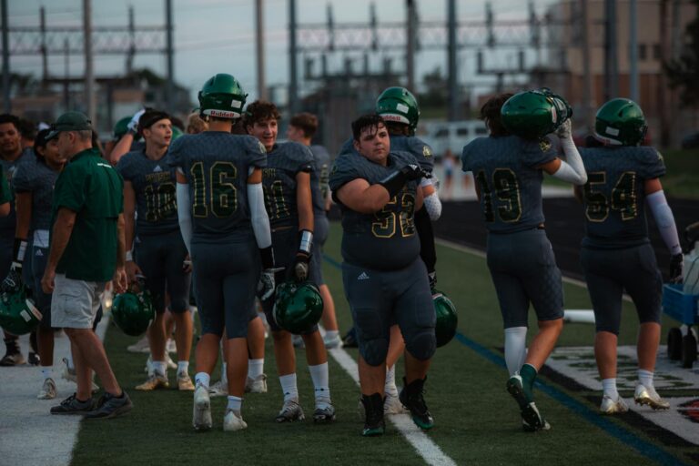 Football players and coaches on the sideline during a high school game.