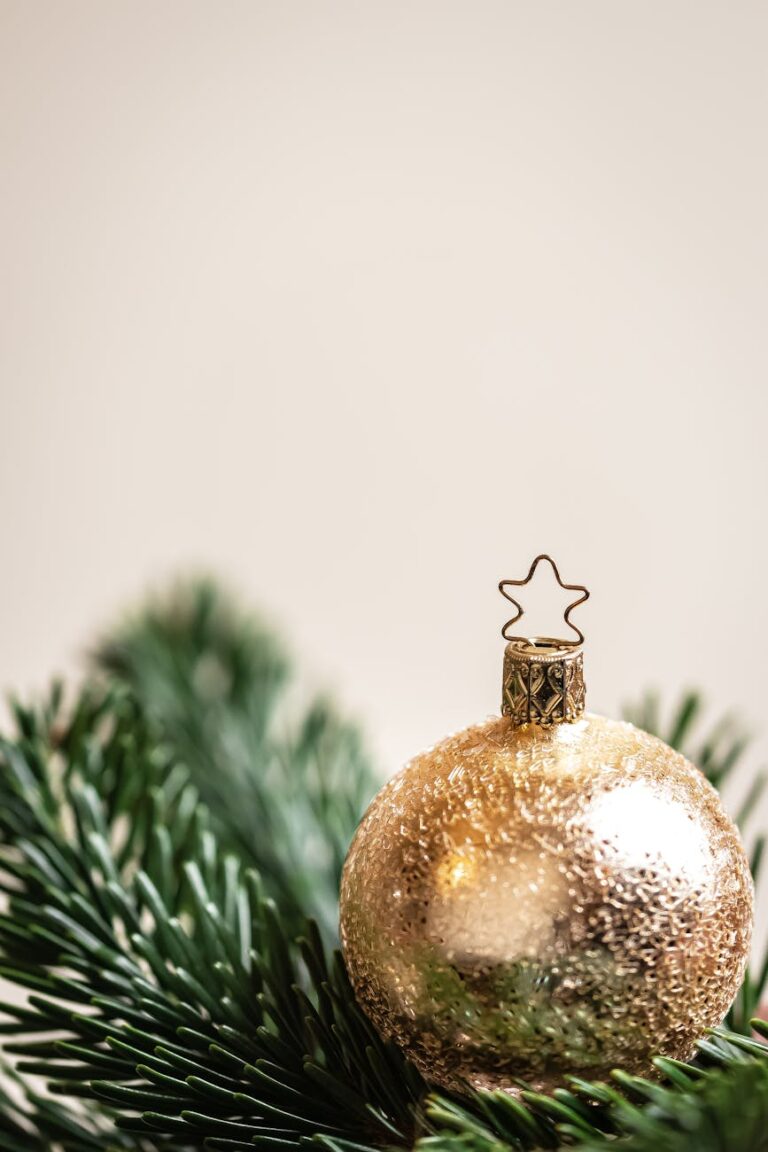 Close-up of a shiny gold ornament on pine branch, perfect for festive decor.