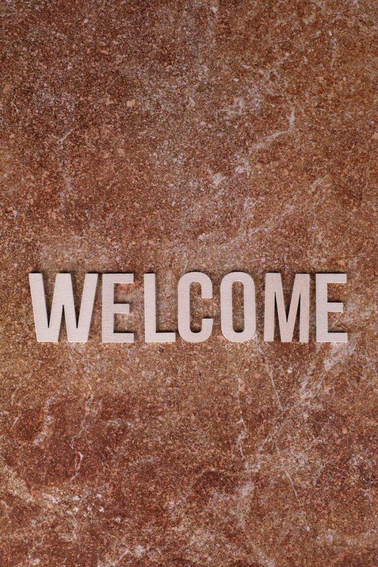 Close-up of a 'Welcome' sign on a textured brown stone surface, perfect for hospitality themes.