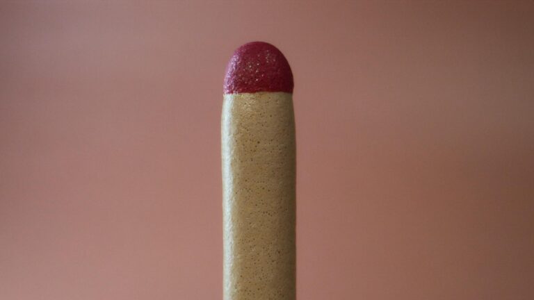 Detailed close-up of a single matchstick focusing on the red tip in a minimalistic composition.