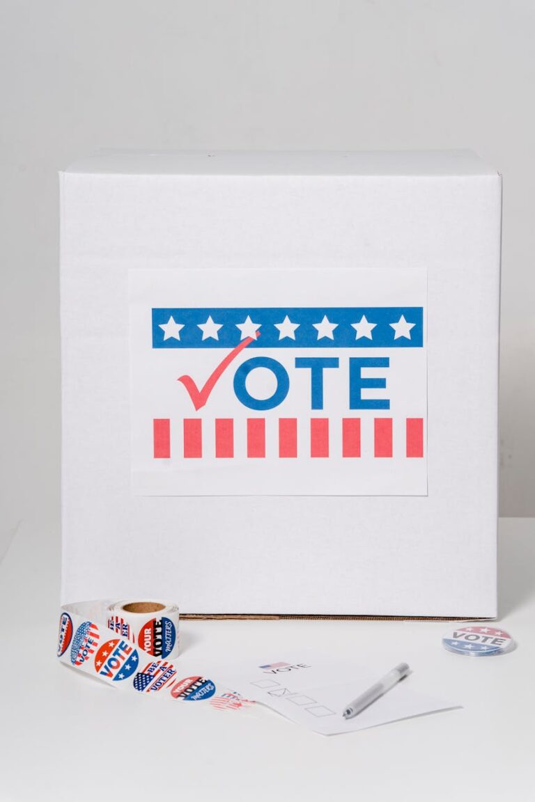 Ballot box with 'Vote' sign and voting stickers on a white background.