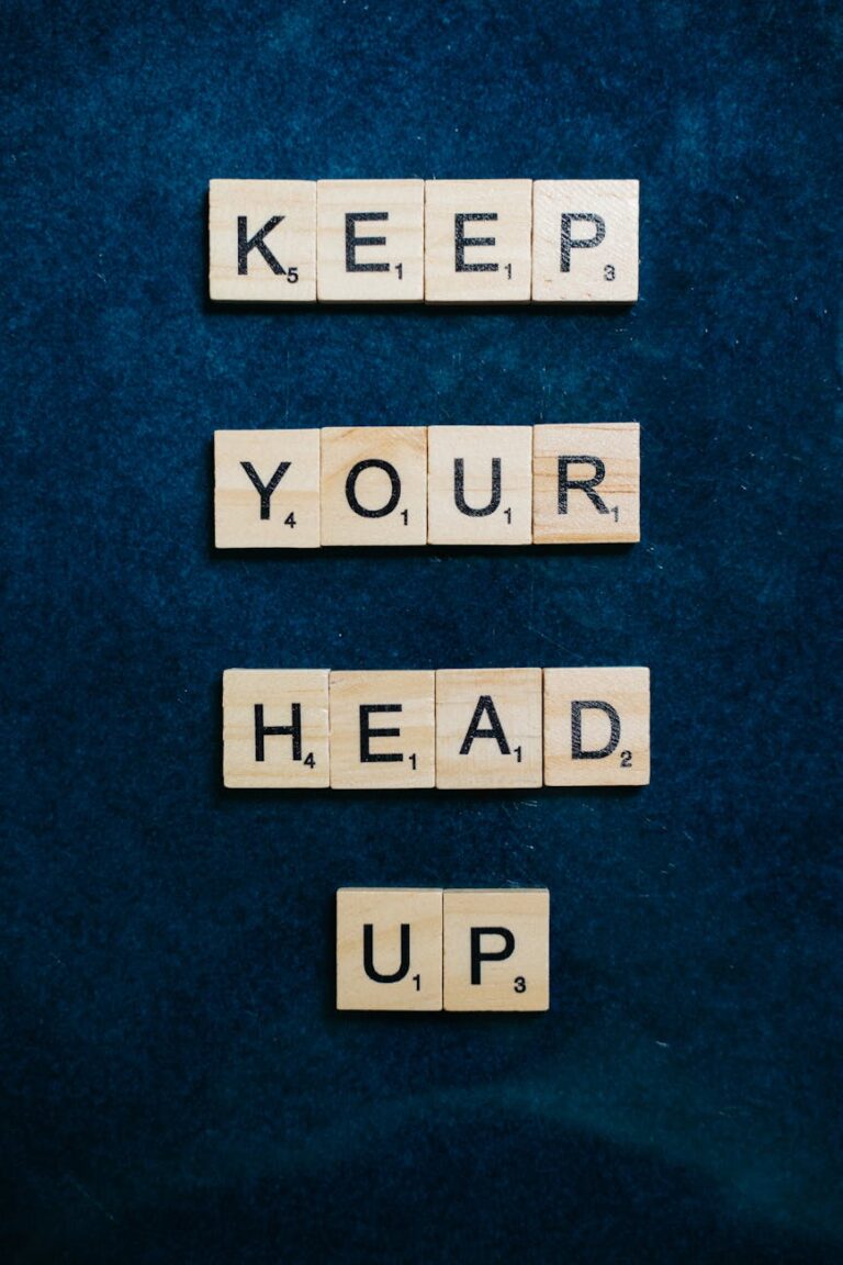 Scrabble tiles spelling 'Keep your head up' on a textured surface.