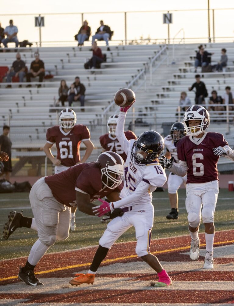 High school football players in action on a sunny day at the stadium, showcasing teamwork and competition.