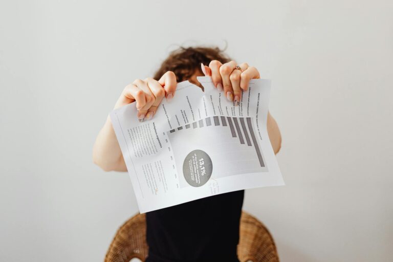 A frustrated individual tearing a printed document with graphs and text.