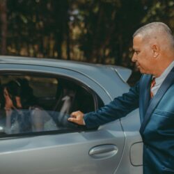 Formal wedding arrival with a bride in a car and an elegantly dressed man opening the door.