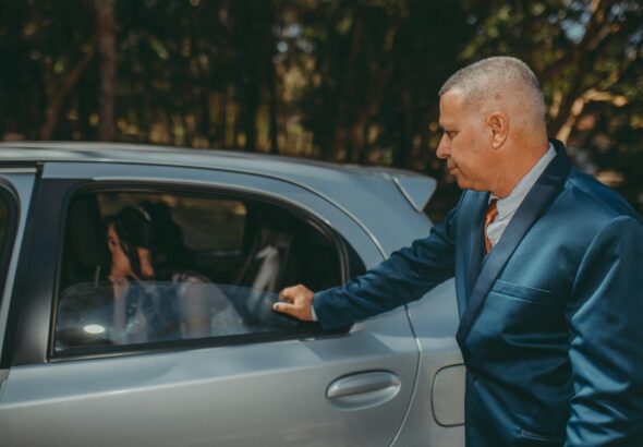 Formal wedding arrival with a bride in a car and an elegantly dressed man opening the door.