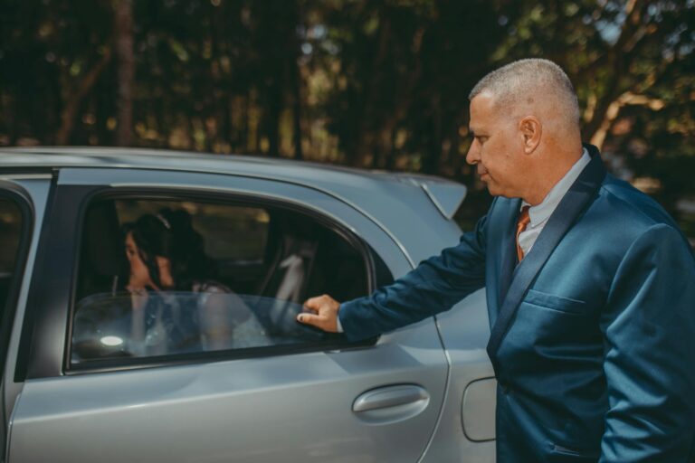 Formal wedding arrival with a bride in a car and an elegantly dressed man opening the door.