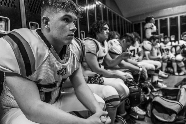 High school football team in a locker room, preparing with focus and intensity.