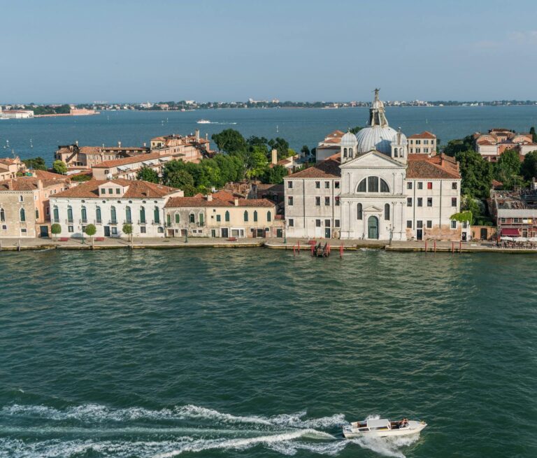 Aerial view capturing classic Venetian architecture on a serene island with clear blue waters.