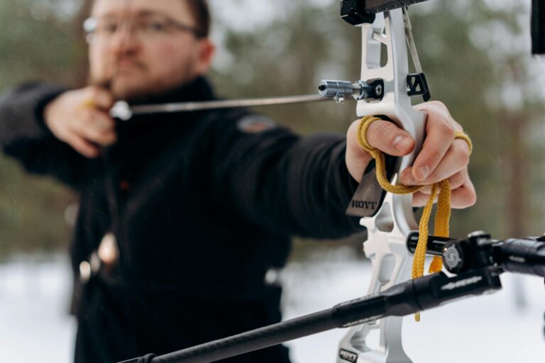 An archer concentrates intensely while aiming a bow outdoors, showcasing skill and precision.