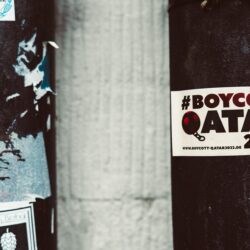 A street pole adorned with a #BoycottQatar2022 sticker highlighting protest themes.