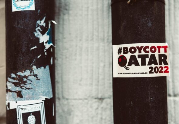 A street pole adorned with a #BoycottQatar2022 sticker highlighting protest themes.