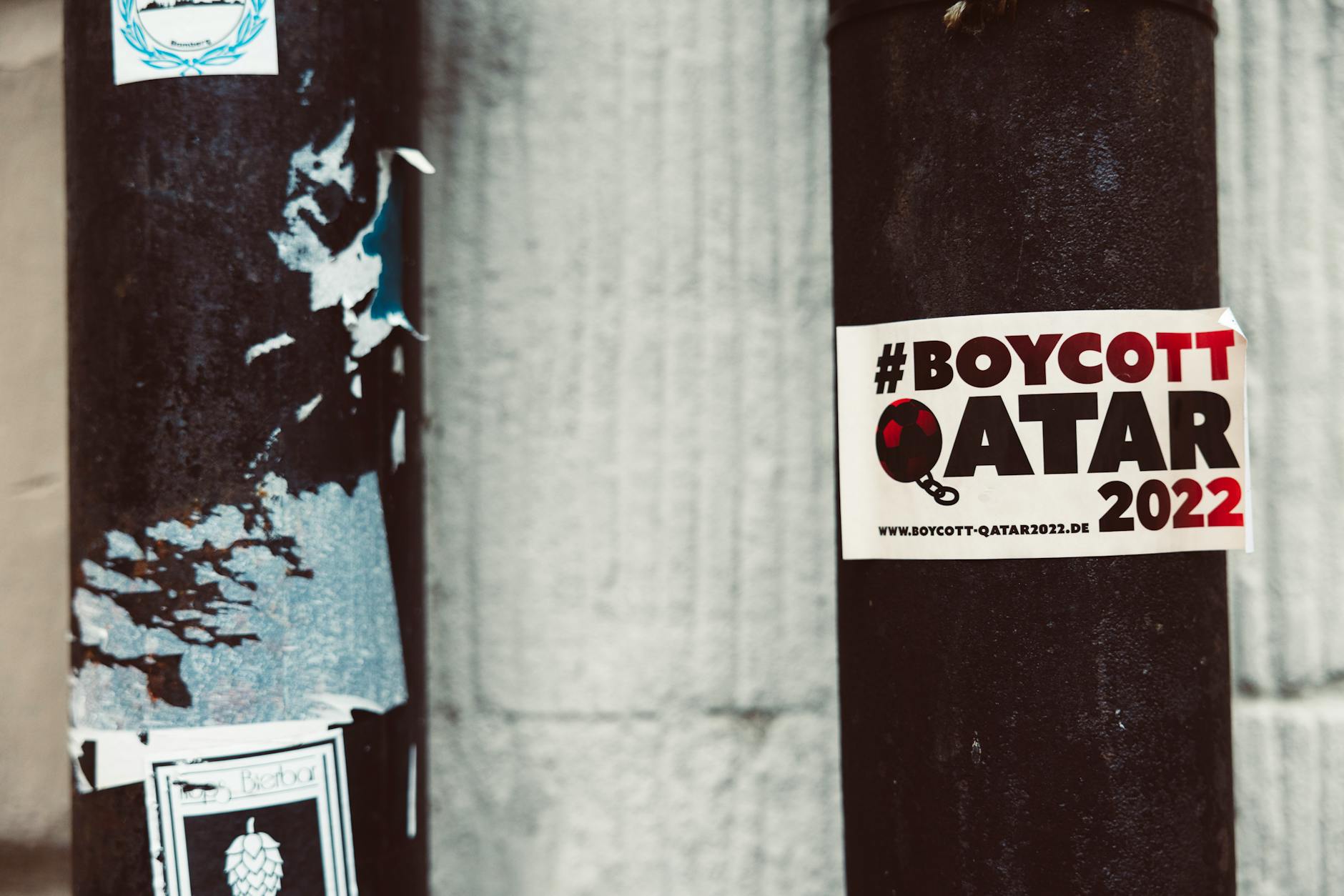 A street pole adorned with a #BoycottQatar2022 sticker highlighting protest themes.