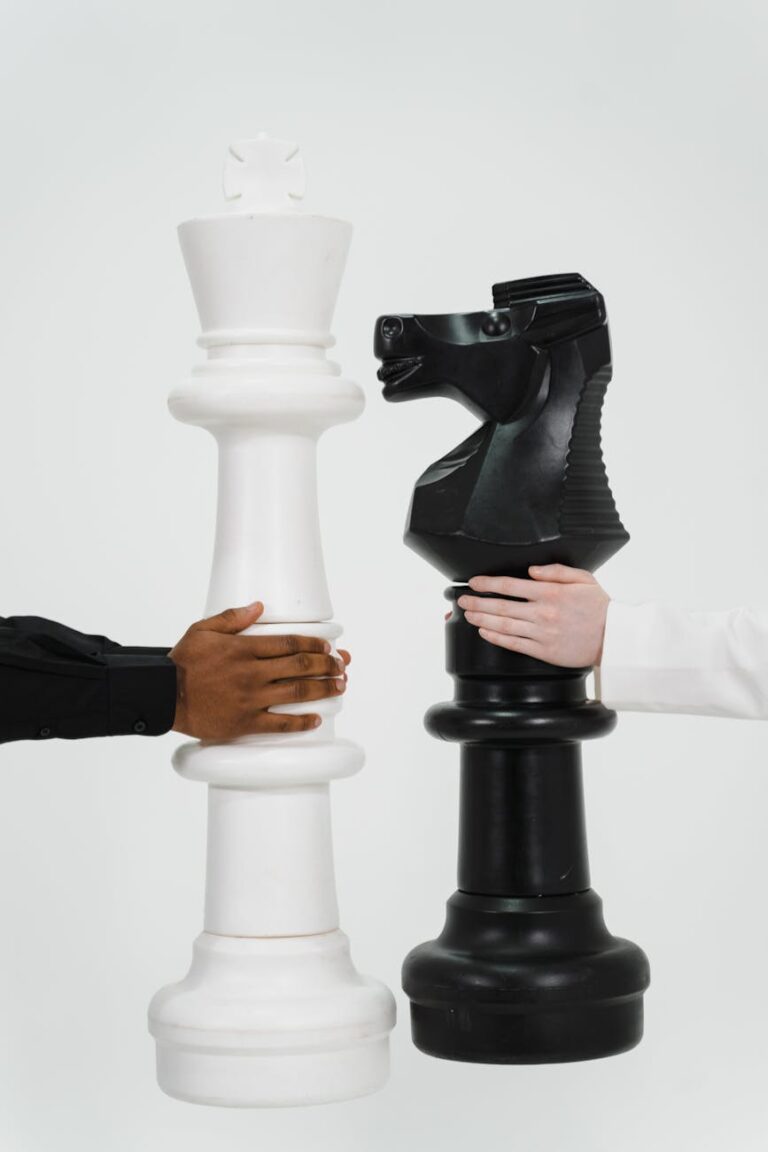Two hands holding giant chess pieces representing strategic thinking and competition.