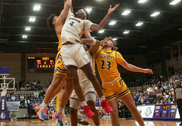 Dynamic basketball game with athletes jumping for the ball during an indoor match.