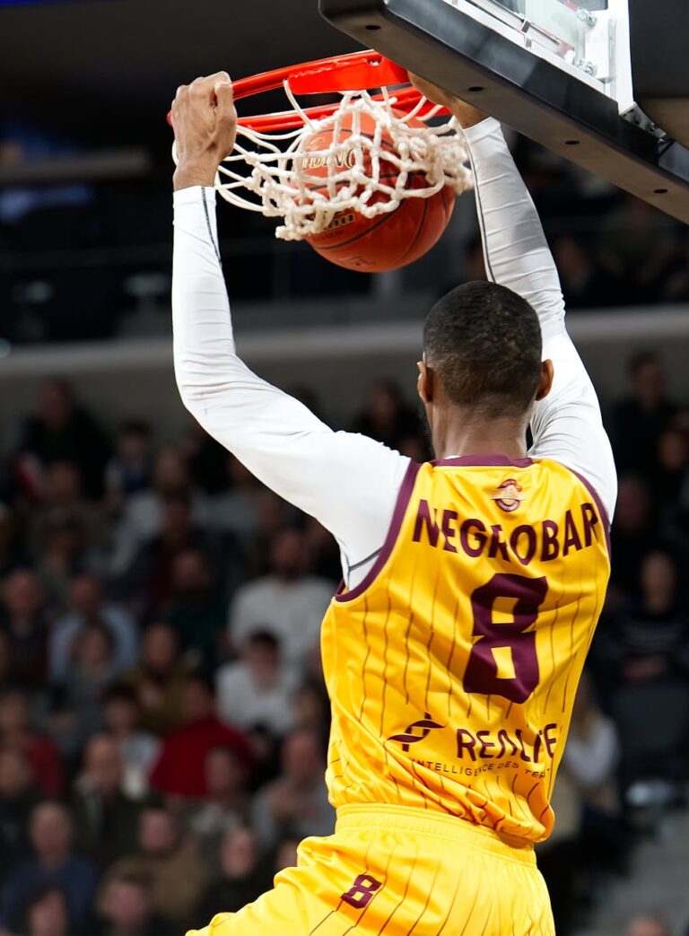 Dynamic shot of a basketball player performing a slam dunk during an intense game.