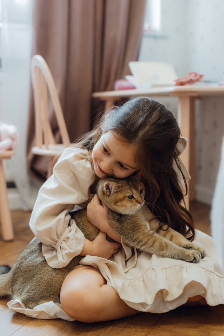 A young girl lovingly hugs her pet cat indoors, showcasing a tender moment of affection and companionship.