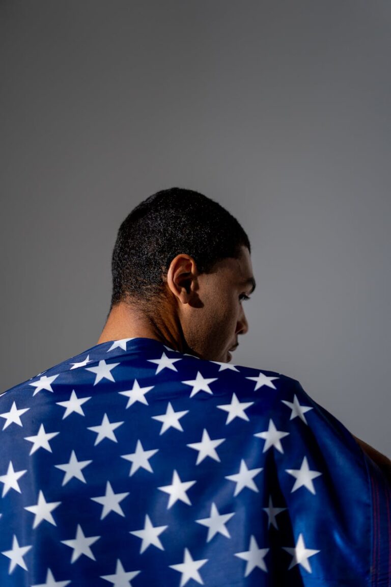Back view of a man wrapped in the American flag symbolizing patriotism and pride.