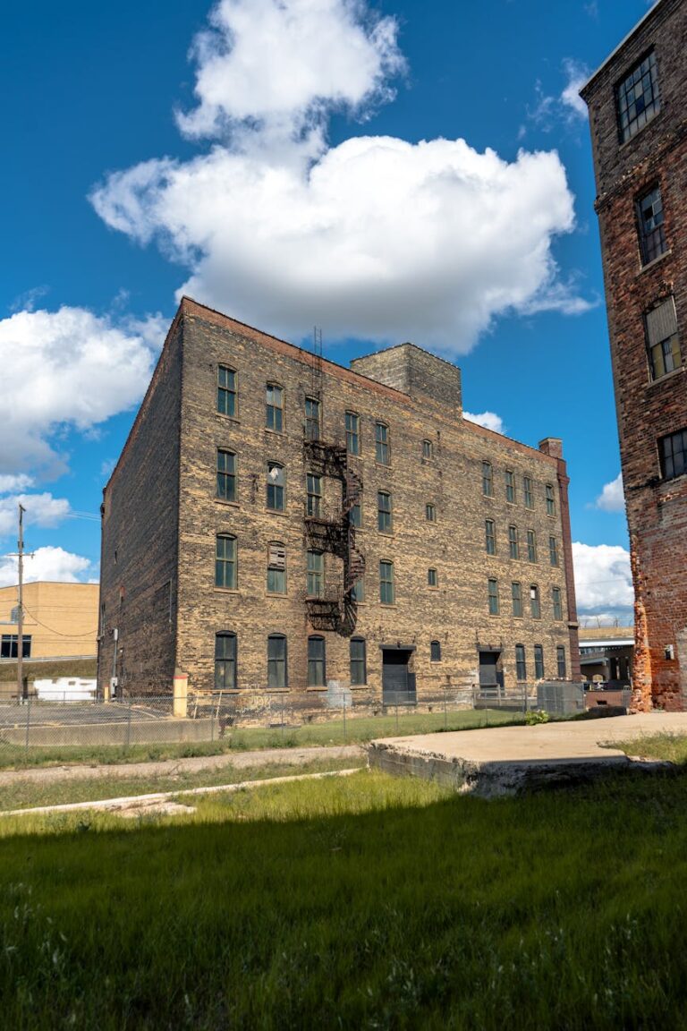 Abandoned brick warehouse with fire escape under a blue sky in Grand Rapids.