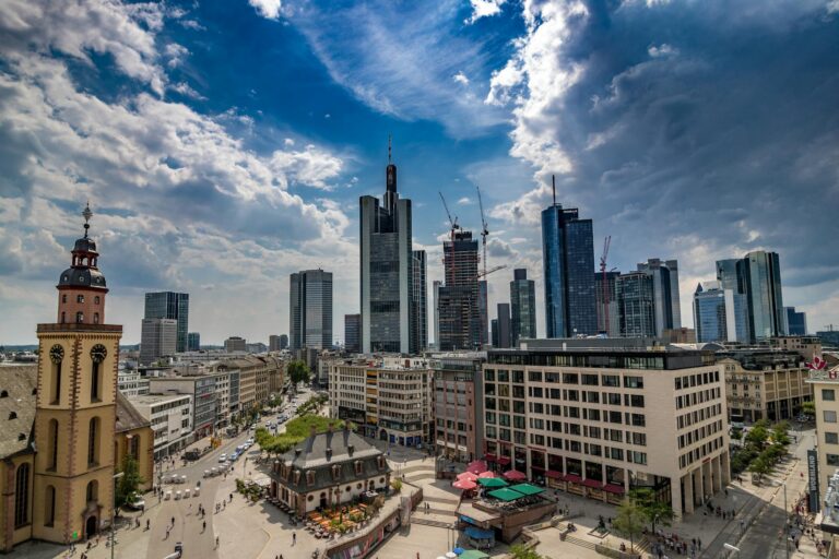 A stunning aerial view captures the modern skyline of Frankfurt, showcasing skyscrapers under a dramatic sky.