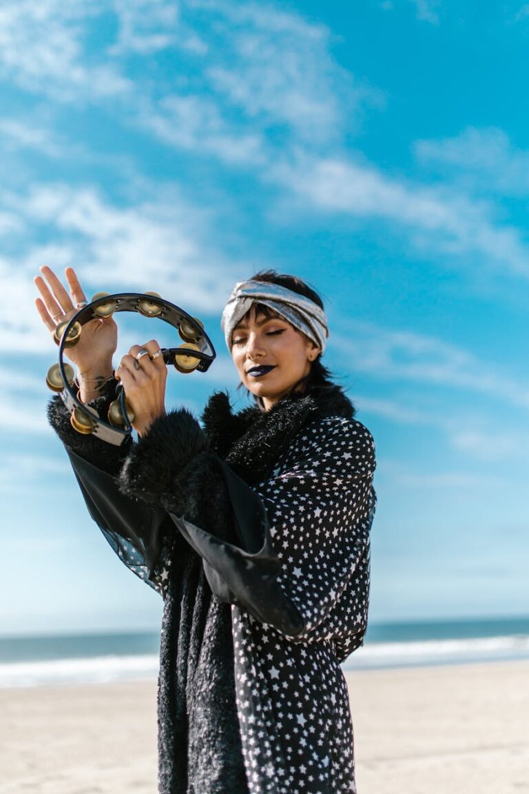 A joyful woman with a tambourine on a sunny beach exuding bohemian vibes.