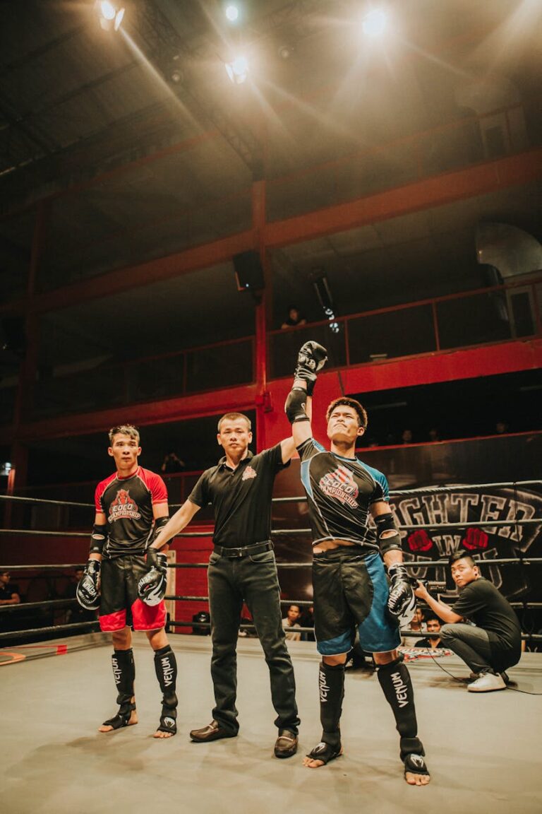 Mixed martial arts match with the winner announced in a boxing ring under bright lights.