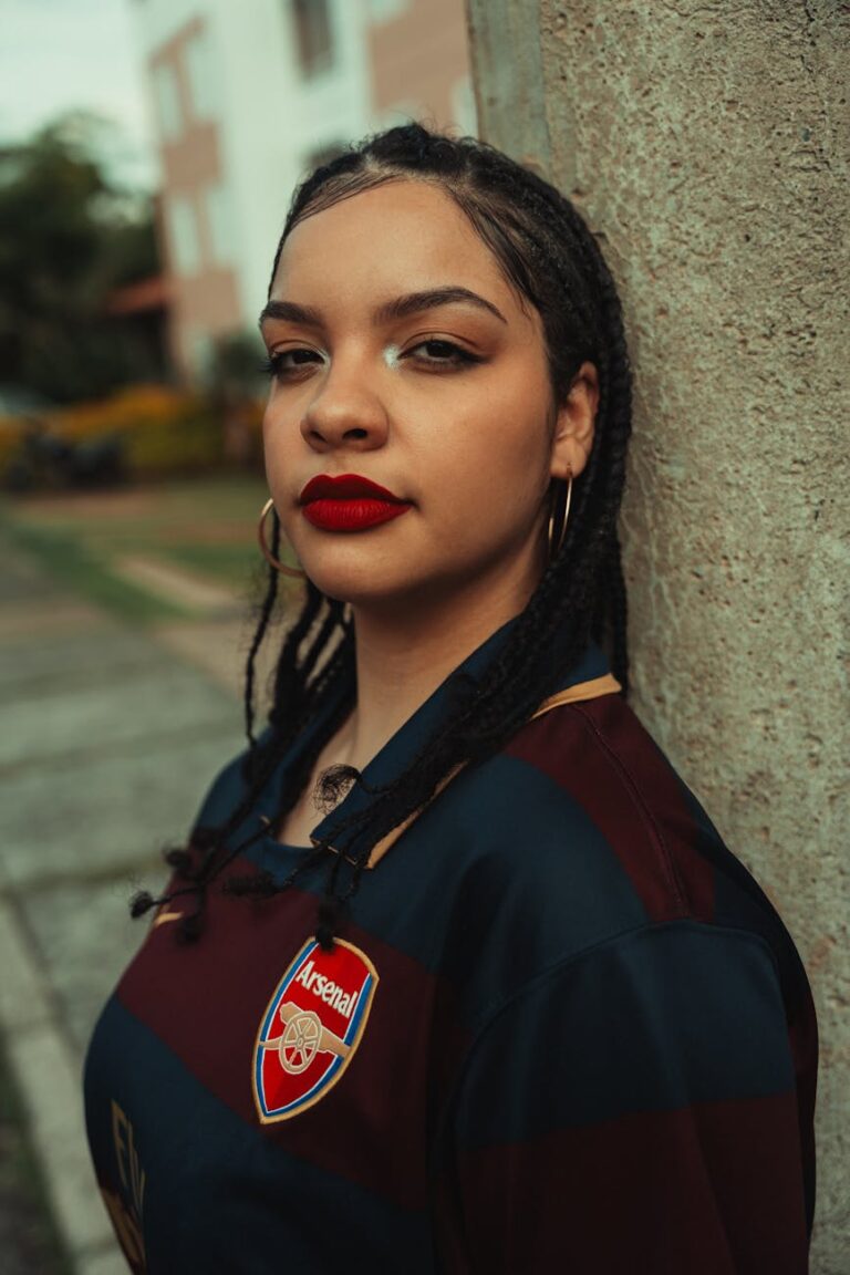 Portrait of a young woman outdoors wearing an Arsenal jersey, vibrant fashion and confident expression.