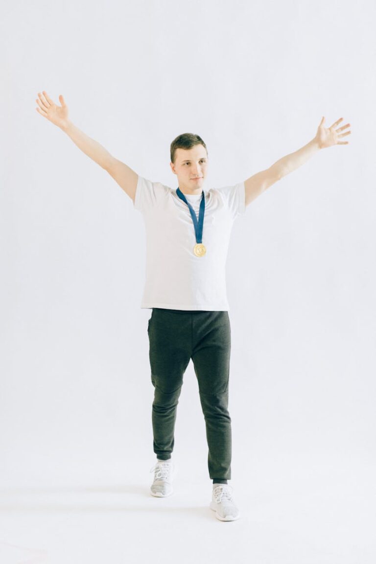Man celebrating victory with a gold medal, arms raised, on a white background.